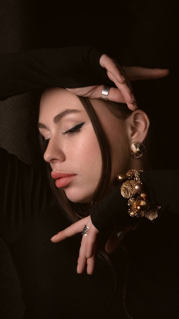 Студийный портрет: руки у лица, тёмный фон, украшения